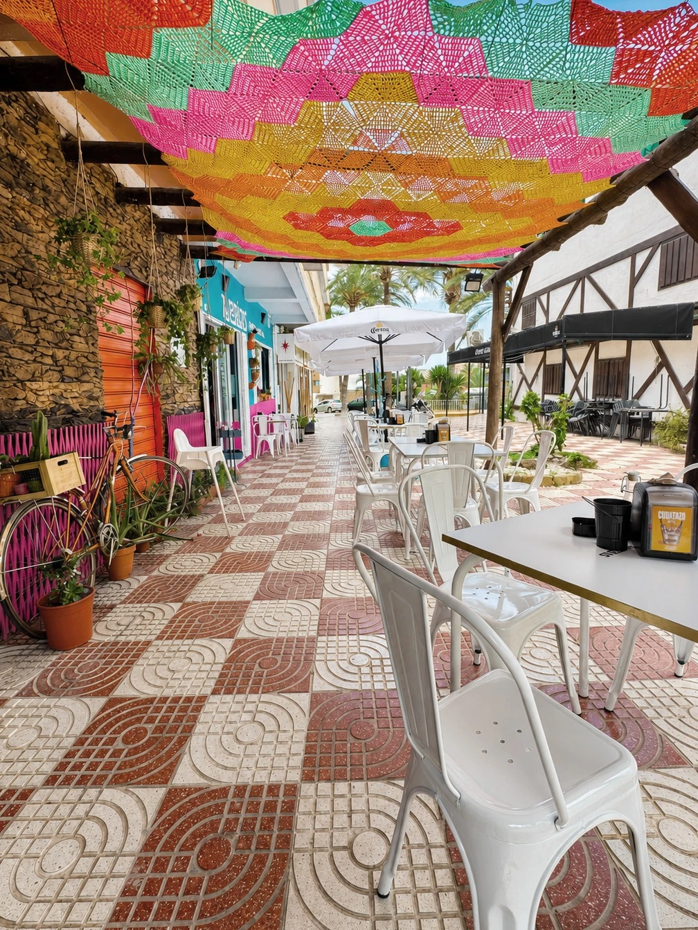 Entrada de Alebrijes Tapería Mexicana bajo un cielo tejido de toldos de colores